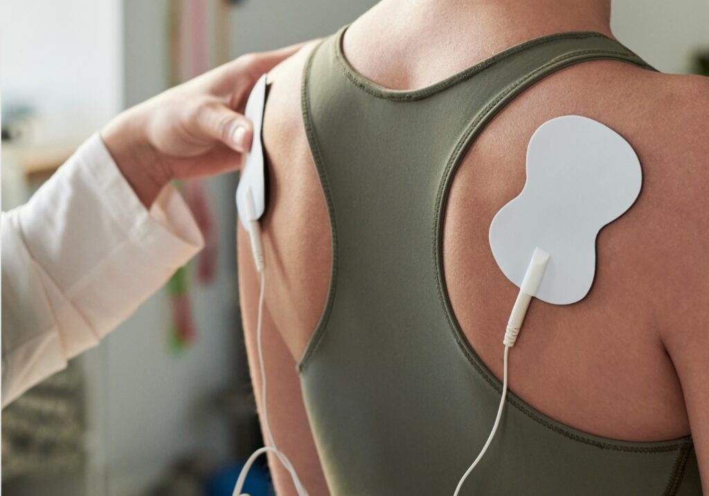 Elektrotherapie an der Schulter mit medizinischen Klebeelektroden.