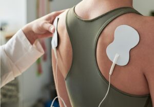 Elektrotherapie an der Schulter mit medizinischen Klebeelektroden.