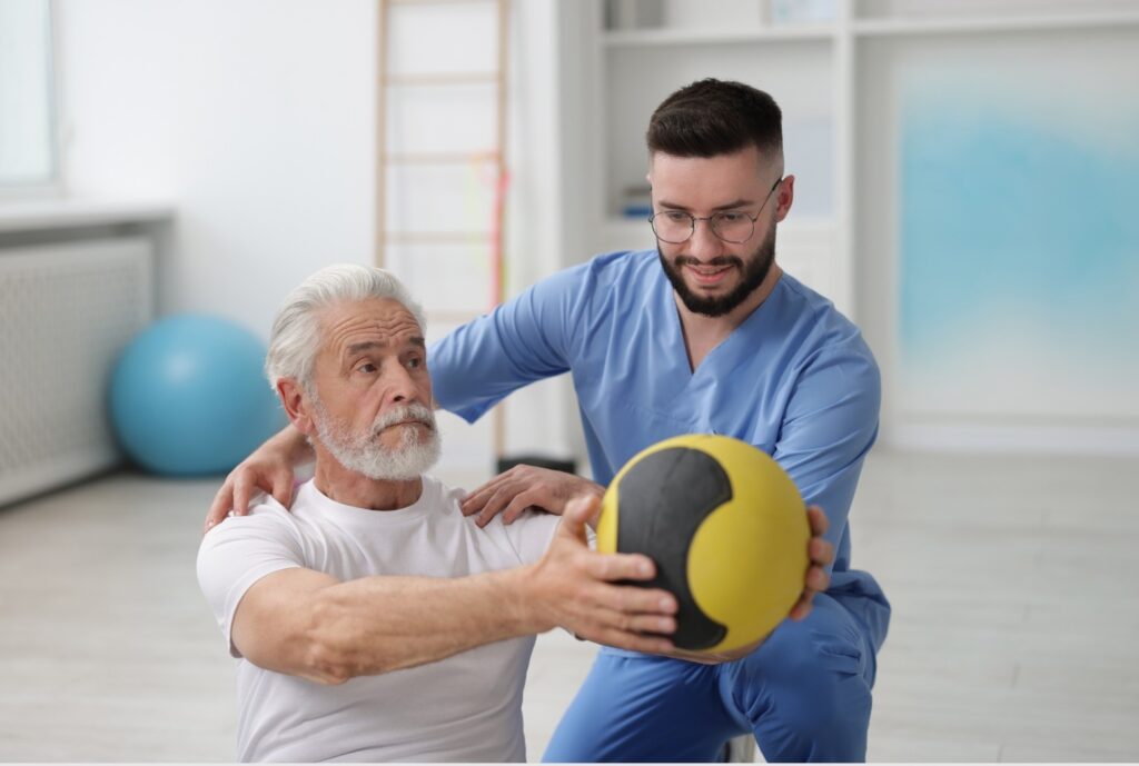 Senior führt gemeinsam mit Physiotherapeuten aktive Krankengymnastik-Übungen durch.
